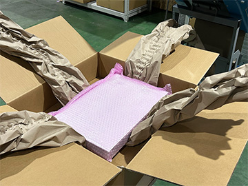 段ボール箱の中央にピンク色の製品が置かれ、周囲を紙製緩衝材が覆っている状態を撮影した画像